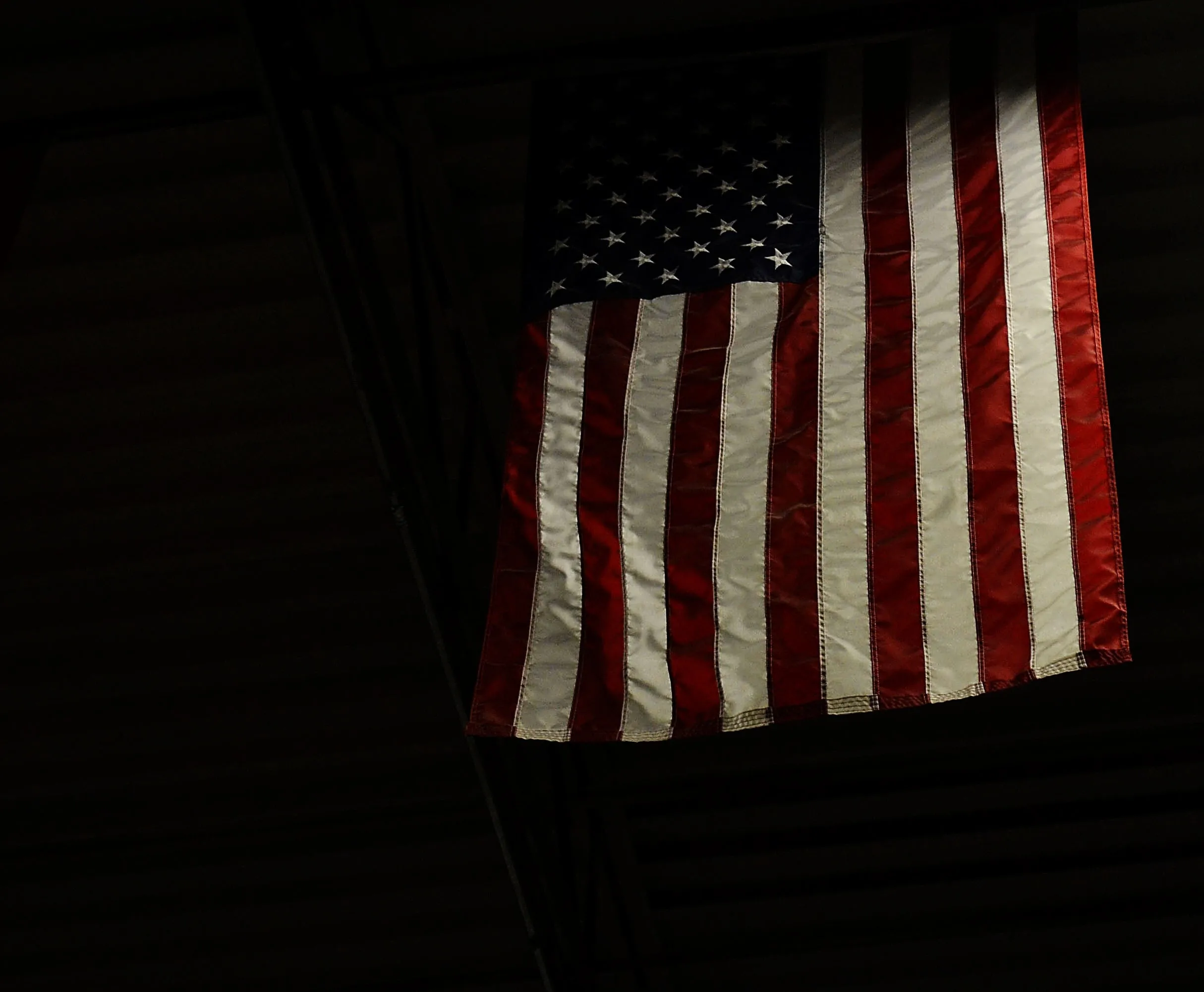 American flag hanging from the rafters of a dark garage gym